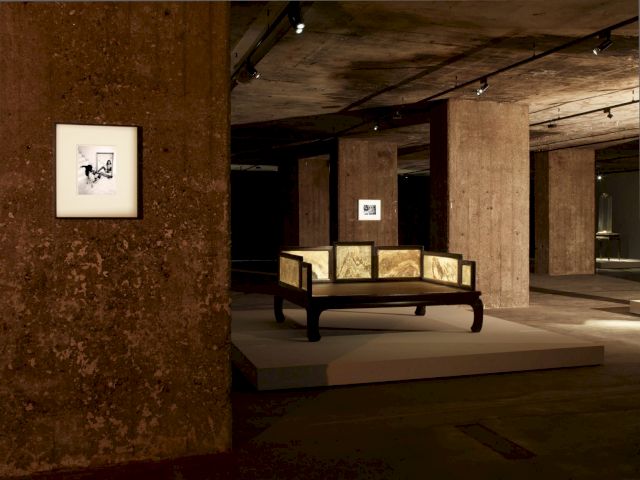 Exhibition view of The Feuerle Collection, 'Lohan Bed', Qing Dynasty, 17 Jichi wood. Approx. 149 x 204 x 100cm. In the background works by Nobuyoshi Araki. Photo: Nic Tenwiggenhorn / VG Bild-Kunst, Bonn. © The Feuerle Collection