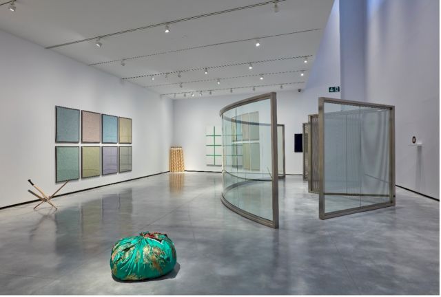 Exhibition view – ‘Corona republicana 0’ (2014) Juan Luis Moraza; ‘Papel moneda’ (2007) Ignasi Aballí; ‘Untitled (Candles)’ (2012) Philippe Parreno; ‘Bottari, Oct.22 2000’ (2000) Kimsooja; ‘Pavilion For Showing Rock Videos/Films (Desing I)’ (2012) Dan Graham and ‘DOLOSO. Barrita’ (2017) Ana Prada at Museum of Contemporary Art Helga de Alvear. Photo: Joaquín Cortés